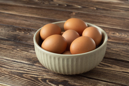 Uncooked eggs in a bowl on wooden background.の写真素材