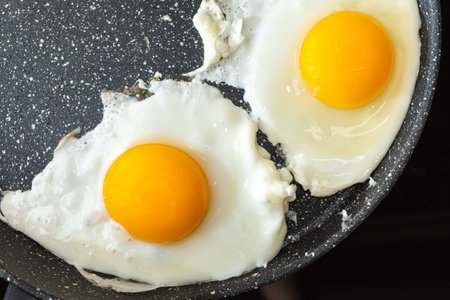 Fried eggs in a frying pan on electric stove top view.の写真素材