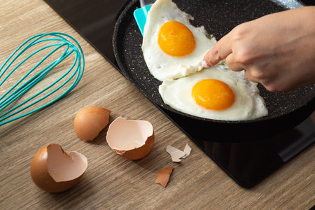Frying eggs in a frying pan and eggshell on the table.の写真素材