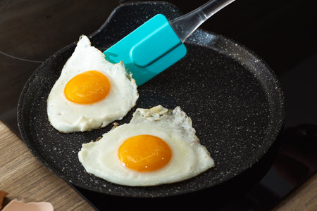 turn over of fried eggs with spatula in a frying pan.の写真素材