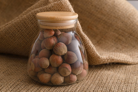 hazelnut inside glass container on burlap backgroundの写真素材