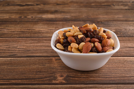 Various nuts in ceramic plate on wooden tableの写真素材