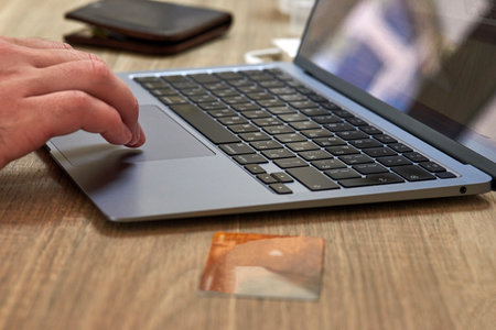 Credit card on table near the laptop, hand on laptop keyboard, internet payment conceptの写真素材
