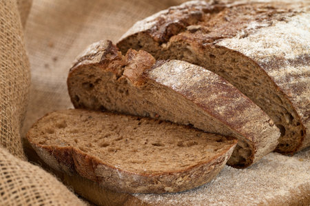 Sliced rye bread sprinkled with white powder on burlap close-up