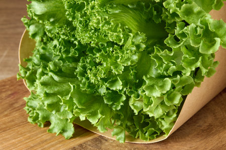 Fresh green lettuce in cartoon box laying on wooden cutting boardの写真素材