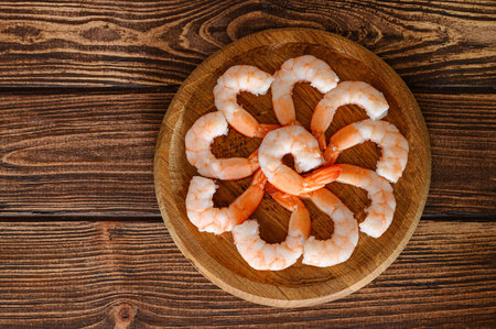 Top view of group of shrimps on wooden plate on wooden table, food backgroundの写真素材