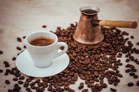 Coffee turk and cup of coffee on burlap background. coffee beans isolated on white background. roasted coffee beansの写真素材