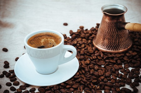 Coffee turk and cup of coffee on burlap background. coffee beans isolated on white background. roasted coffee beansの写真素材