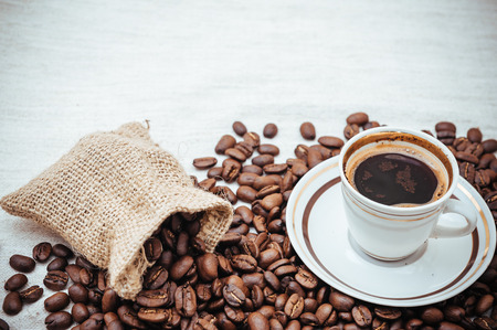 Coffee cup and roasted beans on burlap backgroundの写真素材