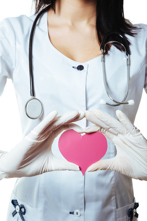 Positive female doctor standing with stethoscope and red heart symbol isolated on white background.の写真素材