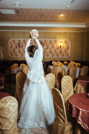 Gorgeous bride blonde in wedding dress in luxury interior with diamond jewelry posing at home and waiting for groom. Romantic rich beautiful brunette bride in a luxurious wedding dress in elegant expensive interiorの写真素材