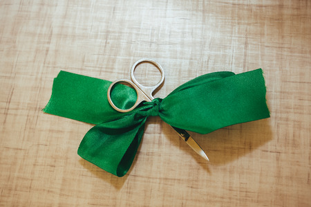Scissors cut green silk ribbon on house backgroundの写真素材