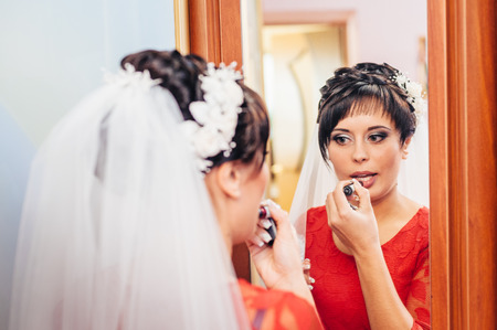 Preparation of the bride. girl with lipstick. Woman looking at the mirror and she is putting a lip glossの写真素材