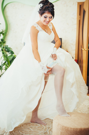 Bride putting a wedding garter on her leg.の写真素材