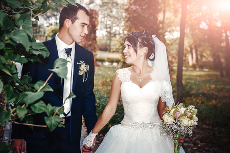 Young couple kissing in wedding gown. Bride holding bouquet of flowers.の写真素材