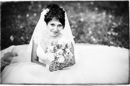 Portrait of beautiful young bride holding bright bouquet of flowers in hands.の写真素材