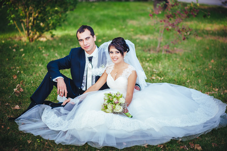 Young couple kissing in wedding gown. Bride holding bouquet of flowers.の写真素材
