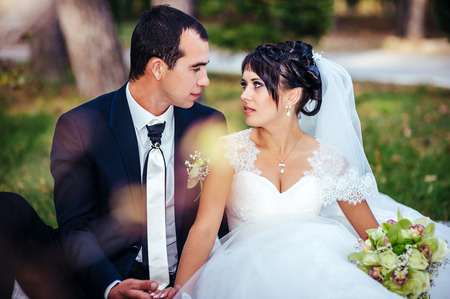 Young couple kissing in wedding gown. Bride holding bouquet of flowers.の写真素材