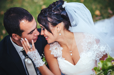 Young couple kissing in wedding gown. Bride holding bouquet of flowers.の写真素材