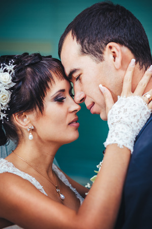 Young couple kissing in wedding gown. Bride holding bouquet of flowers.の写真素材