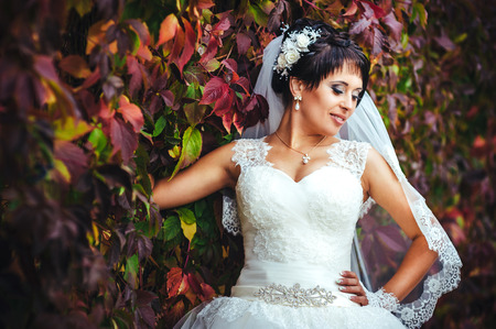 portrait of beautiful young bride holding bright bouquet of flowers in hands. wedding celebration. reception. nature green background. woman alone outdoors in park.の写真素材