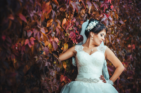 portrait of beautiful young bride holding bright bouquet of flowers in hands. wedding celebration. reception. nature green background. woman alone outdoors in park.の写真素材