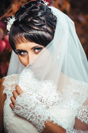 portrait of beautiful young bride holding bright bouquet of flowers in hands. wedding celebration. reception. nature green background. woman alone outdoors in park.の写真素材