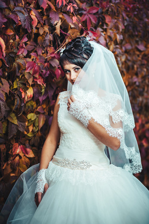 portrait of beautiful young bride holding bright bouquet of flowers in hands. wedding celebration. reception. nature green background. woman alone outdoors in park.の写真素材