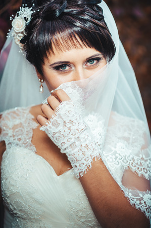portrait of beautiful young bride holding bright bouquet of flowers in hands. wedding celebration. reception. nature green background. woman alone outdoors in park.の写真素材