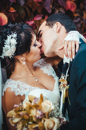 Young couple kissing in wedding gown. Bride holding bouquet of flowers.の写真素材