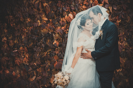 Young couple kissing in wedding gown. Bride holding bouquet of flowers.の写真素材