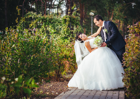 Young couple kissing in wedding gown. Bride holding bouquet of flowers.の写真素材