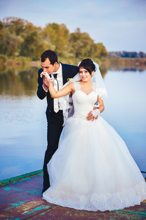 wedding: bride and groom on the seashore. Honeymoon. The bride and groom hugging on the shore of Lake. groom and bride hugging on a green lake. Groom and Bride in a park. wedding dress. Bridal wedding bouquet of flowersの写真素材