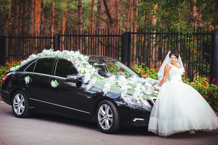 The bride and groom kissing near a black carの写真素材