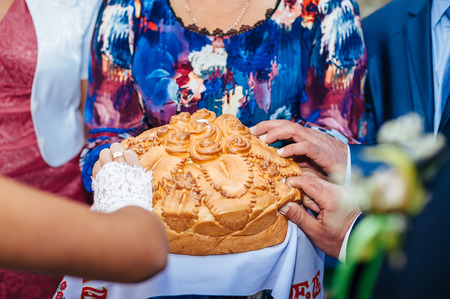 Groom holding slice of traditional wedding round loaf and bride salt itの写真素材