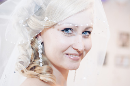 Bride getting ready. beautiful bride in white wedding dress with hairstyle and bright makeup. Happy sexy girl waiting for groom. Romantic lady in bridal dress have final preparation for weddingの写真素材