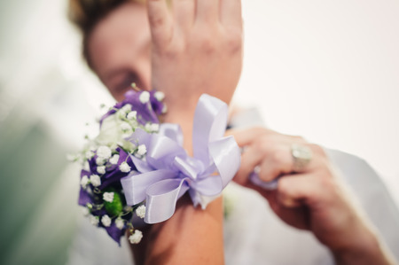 a brides hand putting the boutonniere flower on a groom.の写真素材