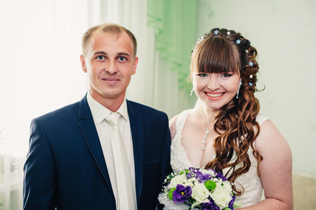 Young wedding couple indoors portrait. Charming bride and groom on their wedding celebration in a luxurious restaurant.の写真素材
