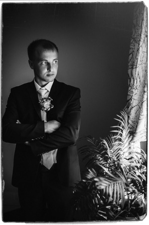 Portrait of a handsome groom in classical interior. The man in the white shirt in the window dress cufflinksの写真素材
