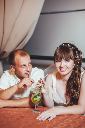 Charming bride and groom drink a mojito on their wedding celebration in a luxurious restaurantの写真素材