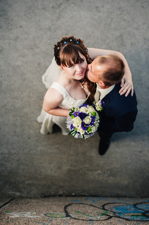Newlyweds embracing and kissing. Top view portrait of bride and groom in a parkの写真素材