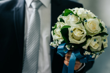 Groom holding bouquet. Concept image - young man waiting woman.の写真素材