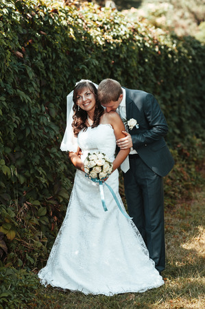 Bride and Groom at wedding Day walking Outdoors on spring nature. Bridal couple, Happy Newlywed woman and man embracing in green park. Loving wedding couple outdoor.の写真素材