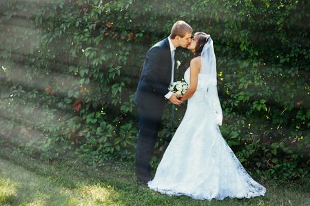Bride and Groom at wedding Day walking Outdoors on spring nature. Bridal couple, Happy Newlywed woman and man embracing in green park. Loving wedding couple outdoor.の写真素材