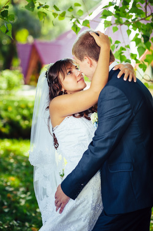 Bride and Groom at wedding Day walking Outdoors on spring nature. Bridal couple, Happy Newlywed woman and man embracing in green park. Loving wedding couple outdoor.の写真素材