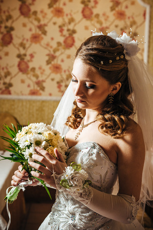 Portrait beautiful bride with bouquet of flowers on luxury interior in wedding day.の写真素材