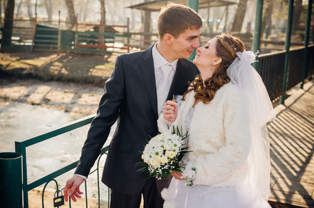 A wedding by the sea. Honeymoon. The bride and groom hugging on the shore of Lake. groom and bride hugging on a green lake. Groom and Bride in a park. wedding dress. Bridal wedding bouquet of flowersの写真素材