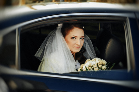 close-up portrait of a pretty shy bride in a car window.の写真素材