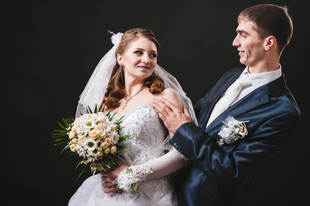 Bride and groom kissing and hugging. wedding photo taken in the studio on a black background.の写真素材