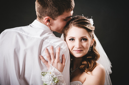 Groom kissing bride on wedding. Black backgroundの写真素材